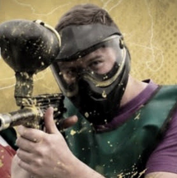 Jugador de paintball apuntando con la marcadora, con la máscara salpicada