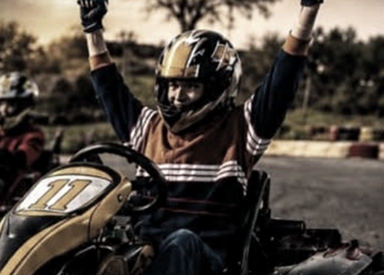 Chico festejando con los brazos en alto arriba de un kart