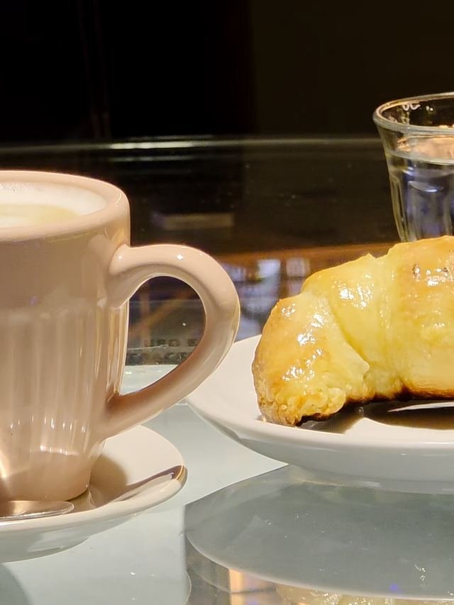 Café con leche y medialuna sobre una mesa hecha con una llanta de competición