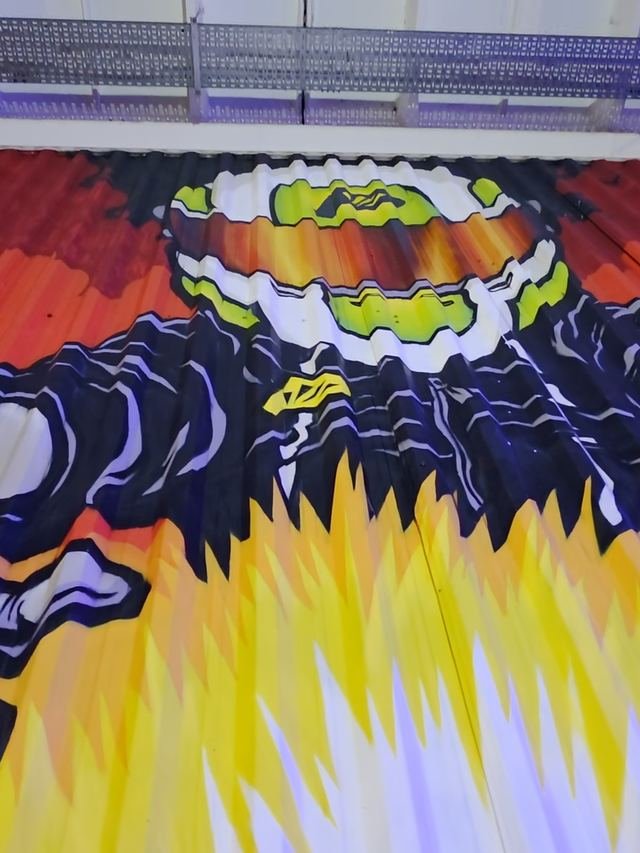 Mural del piloto con casco y llamas en el salón indoor
